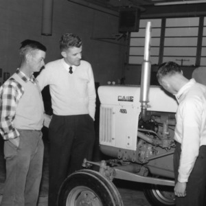 Three 4-H club members examining a tractor at a 4-H tractor show