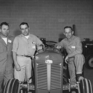 Three 4-H leaders leaning on a tractor at a 4-H tractor program