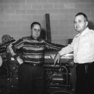 Two 4-H leaders leaning on a tractor at a 4-H tractor program