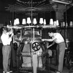 Three men working with knitting machine