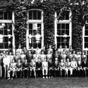 Large group portrait of textile faculty and students in front of Tompkins Hall. Dean Thomas Nelson in front row, seventh from right