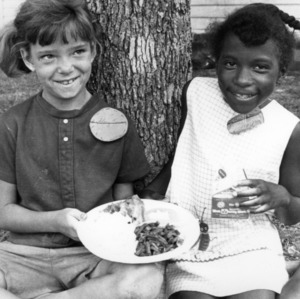 Two 4-H club girls eating together at a picnic, as part of the social activities in the 4-H personal development program
