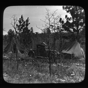 Camp in sandhills with two tents and a Chevrolet automobile from the late 1920s
