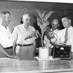 Four unidentified men testing a radioactive tobacco plant at Farm and Home Week in August 1952
