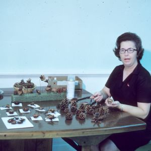 Woman participating in arts and crafts fair (pine cone decorations)