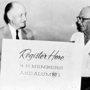 L. R. Harrill holding "register here" sign