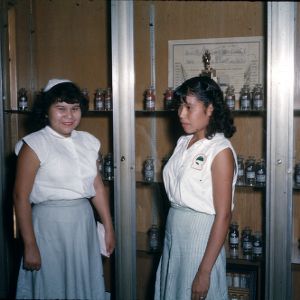Two young Native American women standing in front of a display case