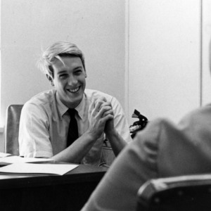 John Poole at desk with other