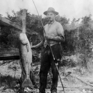 Dr. Carl C. Taylor with fishing pole and a fishy "friend"