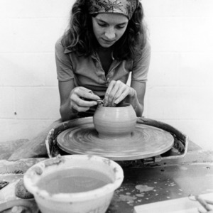 Student molding clay into pottery
