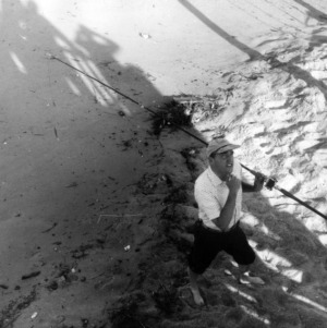 Man with fishing rod walking on beach