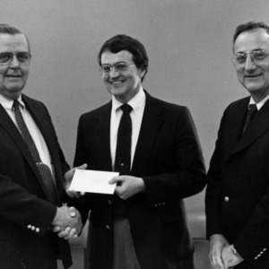 Group of three people, exchanging a check