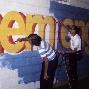 Two people at College of Engineering painting a mural