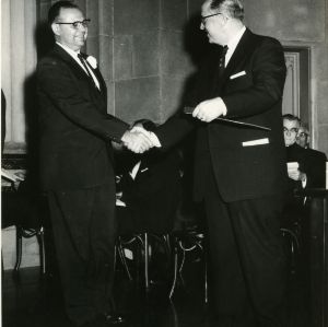 David S. Weaver shaking hands with other man, at event