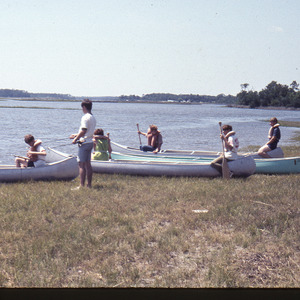 People launching canoes on water, circa June 1970