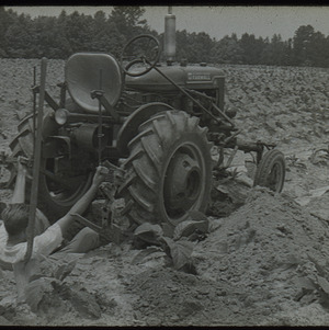 Man working on tractor in field, undated