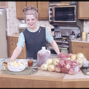 Woman posing with apples in kitchen, circa October 1968