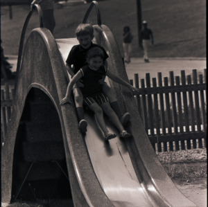 Children playing on slide, circa 1969-1975