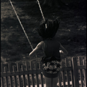 Child playing on swing, circa 1969-1975
