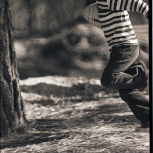 Child running with football, circa 1969-1975