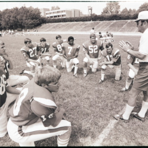 Football coach and players at practice, 1973
