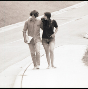 Man and woman walking barefoot, circa 1969-1975