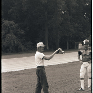 Football coach and player at practice, circa 1969-1975
