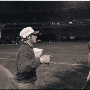 Football coach and player on field, circa 1969-1975
