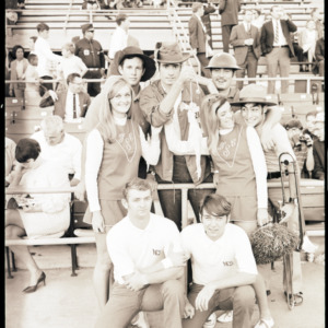 Marching band and cheerleaders posing at football game, 1969
