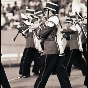 Marching band and spectators at football game, circa 1969-1975