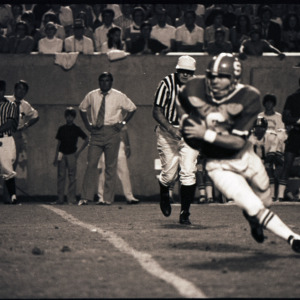 Football player, referees, and spectators at NC State versus East Carolina game, 1973