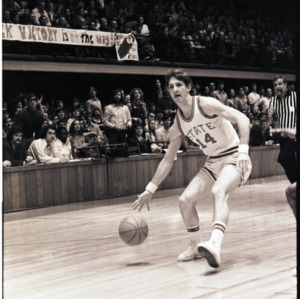 Basketball player, referee, and spectators at NC State versus East Carolina game, circa 1972-1975