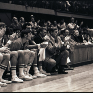 Basketball coach, players, and spectators at NC State versus East Carolina game, circa 1972-1975