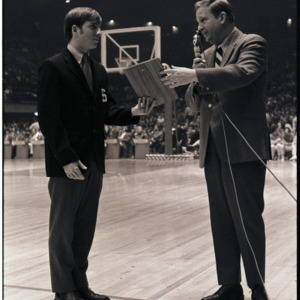 Basketball coach presenting award to player at NC State versus Maryland game, circa 1969-1975