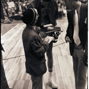 Basketball player and spectators with plaque at NC State versus Maryland ACC title game, 1973