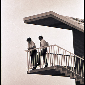 Spectators on balcony watching football scrimmage, circa 1969-1975
