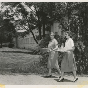 Mary Yarbrough and another woman carrying lab equipment