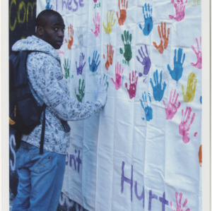 Student Adding Handprint to Wall at These Hands Don't Hurt Event