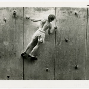 Man student climbing rock wall outside Carmichael Gymnasium