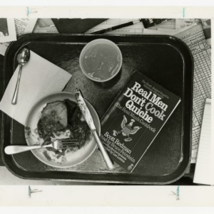 Book Real Men Don't Cook Quiche sits beside a tray of food