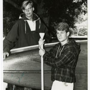 Two students stand with canoe