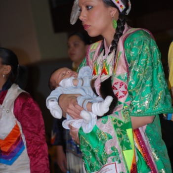 Woman in traditional dress holding baby at NC State's Native American Student Association Pow Wow