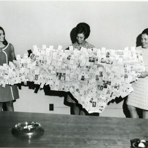 Three people holding collage in the shape of NC state.