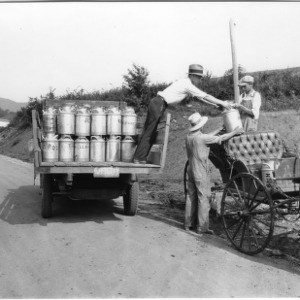 Men unloading and reloading milk cans