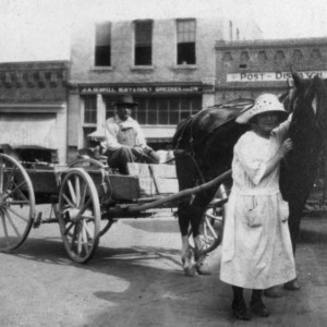 Horse drawn wagon in front of store fronts