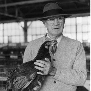 C.J. Maupin, Extension Poultryman, holding prize Utility Red, 1957 Fair