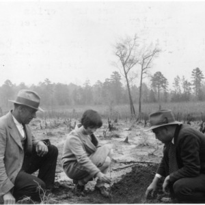 J. W. Sanders showing Erline Woodlier and her father how to transplant black walnut seedlings