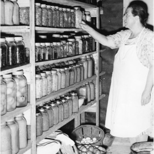 Unidentified woman in cellar with jars of preserved food