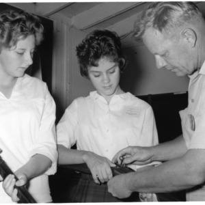 Gun safety demonstration, Bill Hamnett showing Elizabeth Bayne and Jane Wilson how to unload a gun