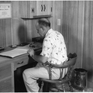 Dairy farmer Elliott L. Harris working in the office of his remodeled home